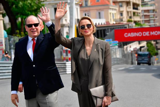 Prince Albert II of Monaco (L) and his wife Princess Charlene of Monaco wave to photographers after meeting members of the Red Cross of Monaco and Italy during a visit ahead of the third practice session at the Monaco street circuit on May 25, 2019 in Monaco, ahead of the Monaco Formula 1 Grand Prix. (Photo by Andrej ISAKOVIC / AFP)