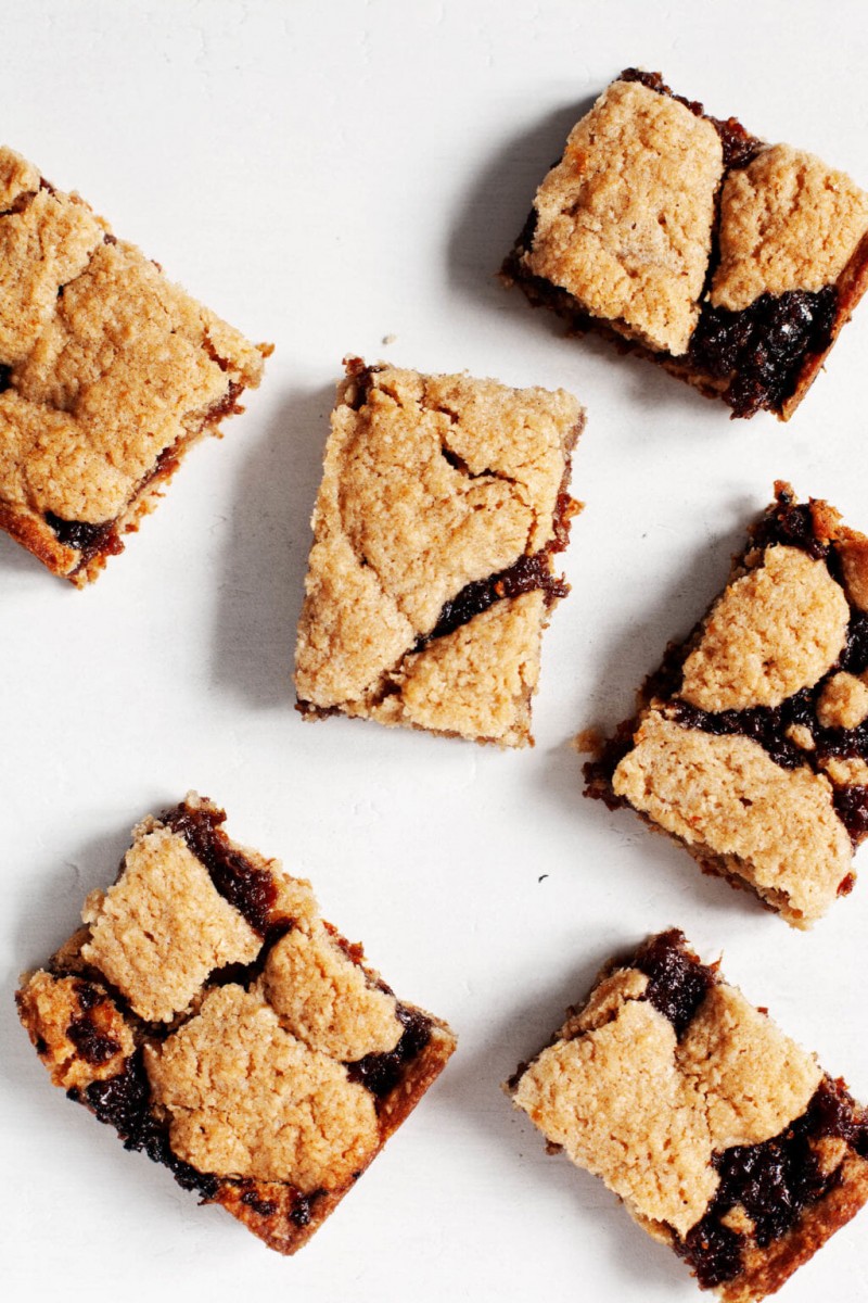 Freshly baked, whole wheat raisin bars are laid out on a bright white surface.