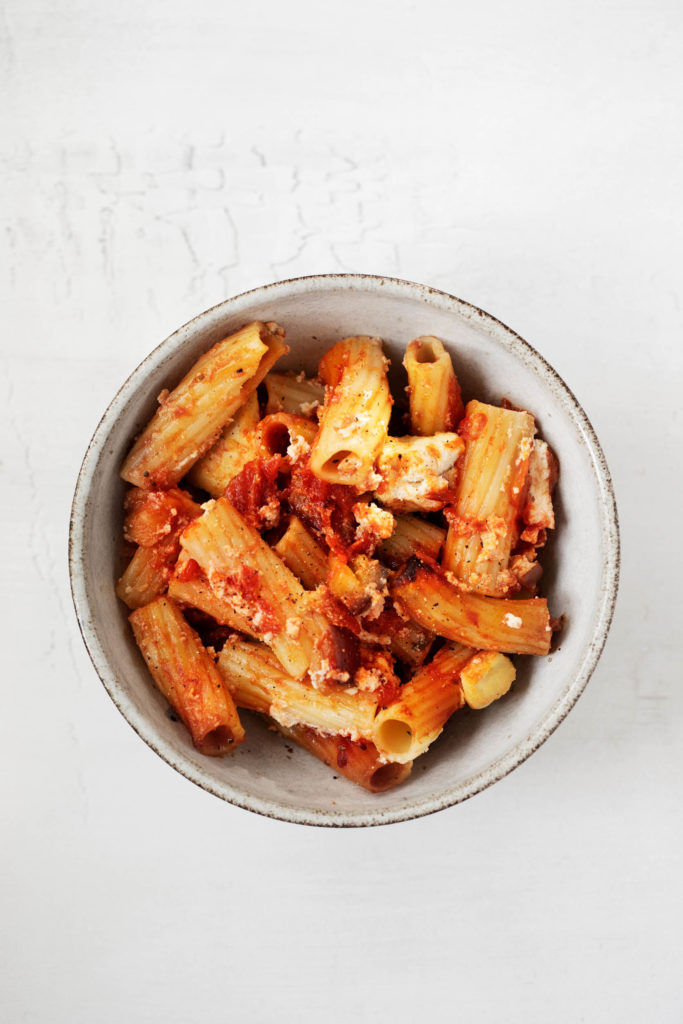 An overhead shot of a bowl of vegan baked rigatoni, made with tomatoes and tofu cashew ricotta.