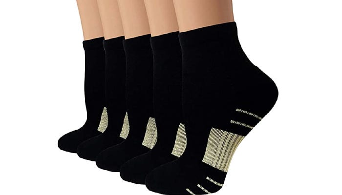 Five ankles are shown in a diagonal line wearing black ankle compression socks with copper stitching against a white background.