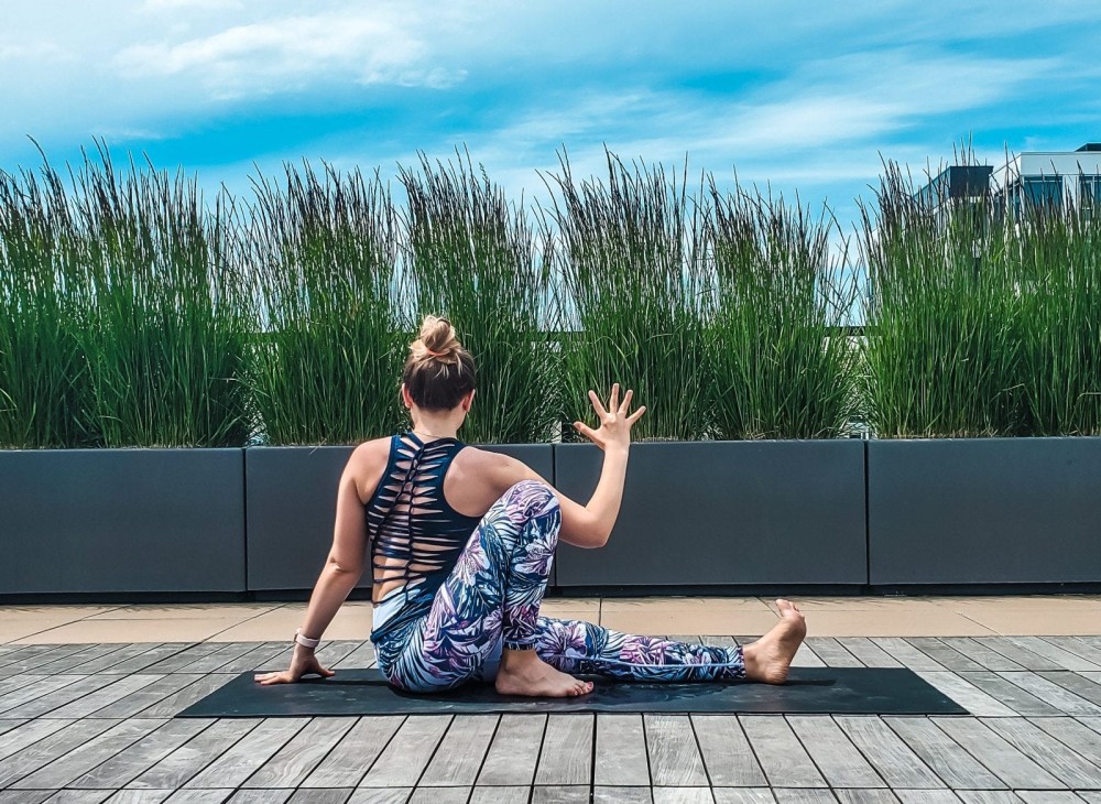 Woman doing yoga seated twist on a rooftop.