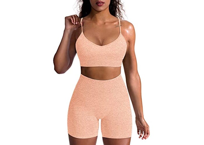 Model in matching peached colored, high-waisted workout shorts and sports bra. 