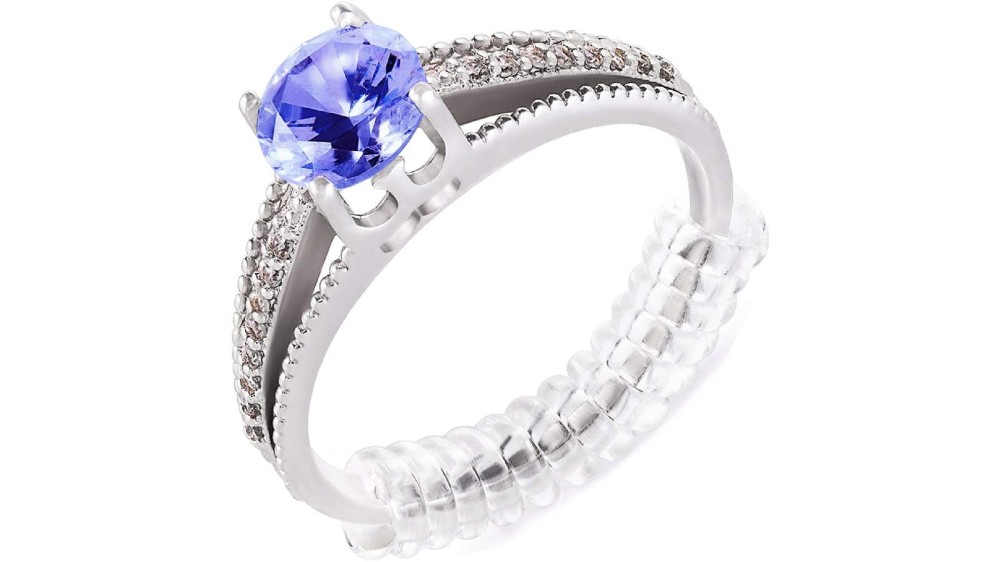 A silver ring that is fitted with a purple gem and a clear band size adjuster.