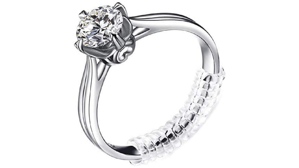 A silver diamond ring with a transparent ring adjuster wrapped around the ring base.