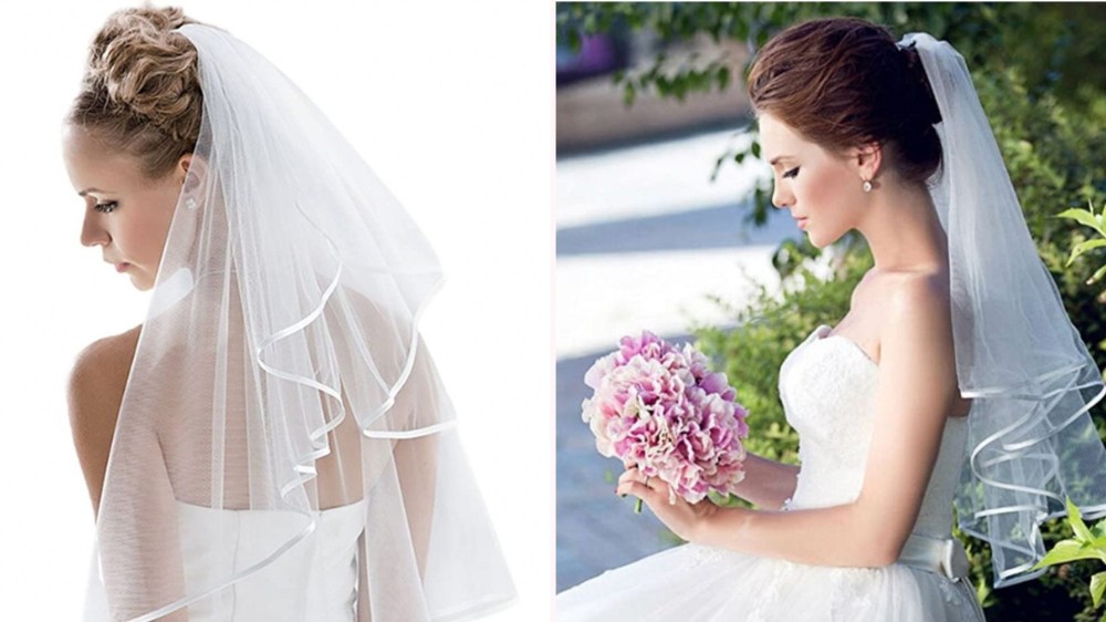 two brides wearing wedding gowns and a white veil with a satin edge that goes down to the waist