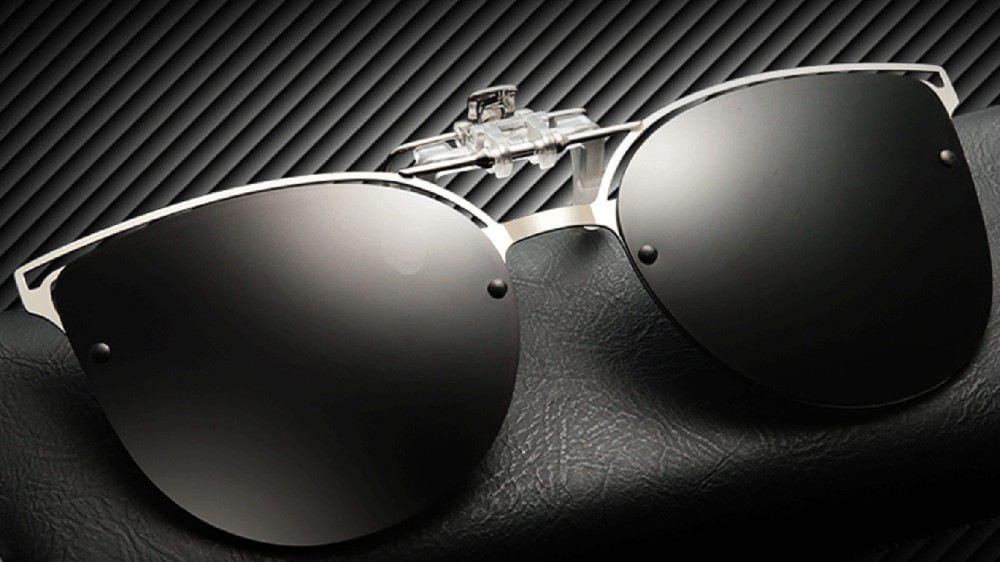 Clip-on sunglasses sit on a black textured surface.