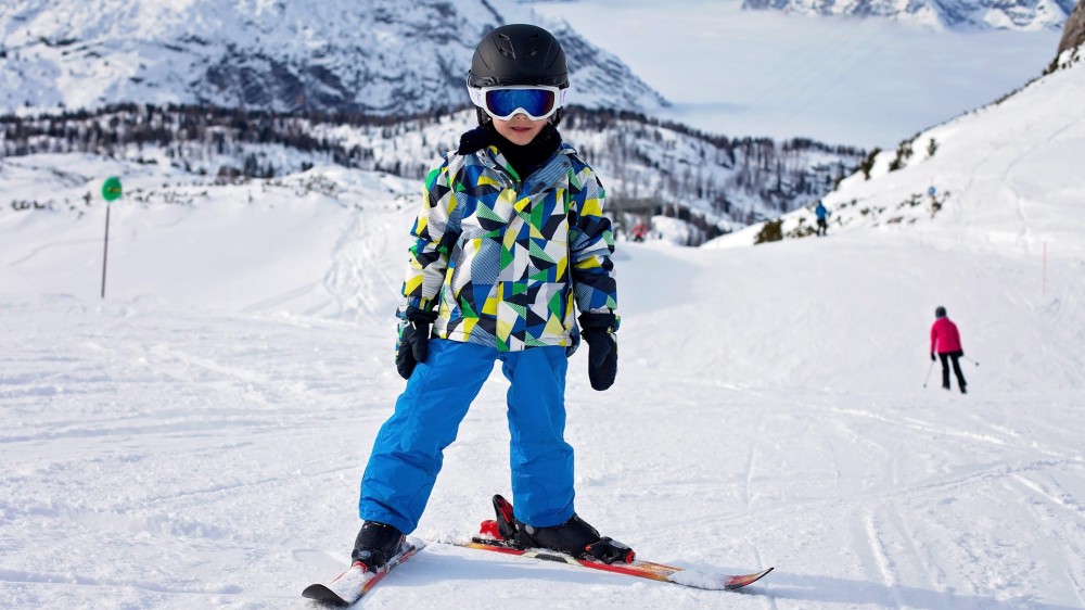 a boy in skiing gear on a hill.