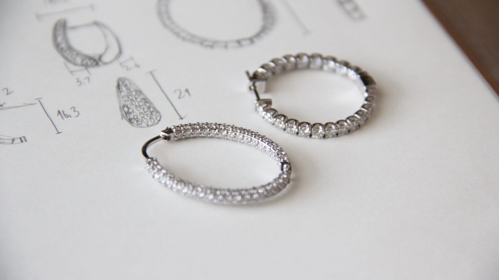 two diamond studded hoop earrings on a piece of paper.