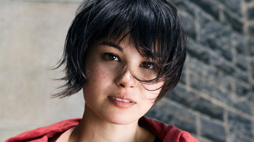 A brunette woman with a round face and a pixie haircut 