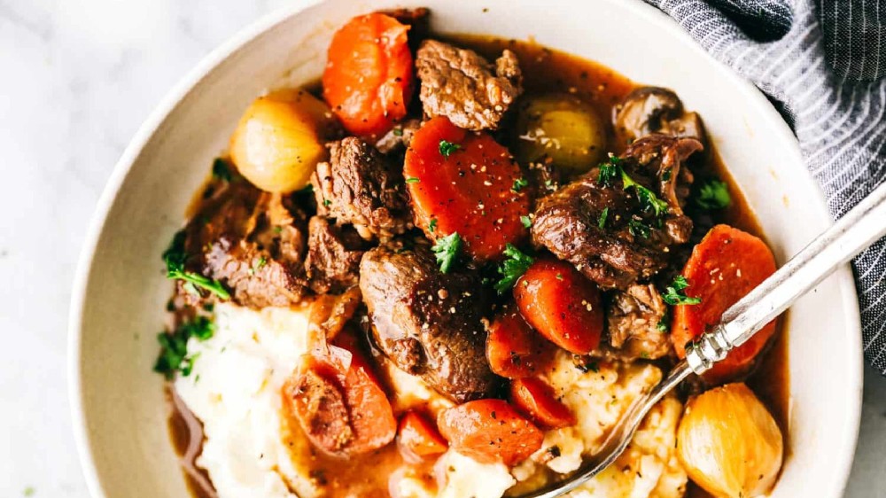 A bowl of hot beef bourguignon with a spoon 