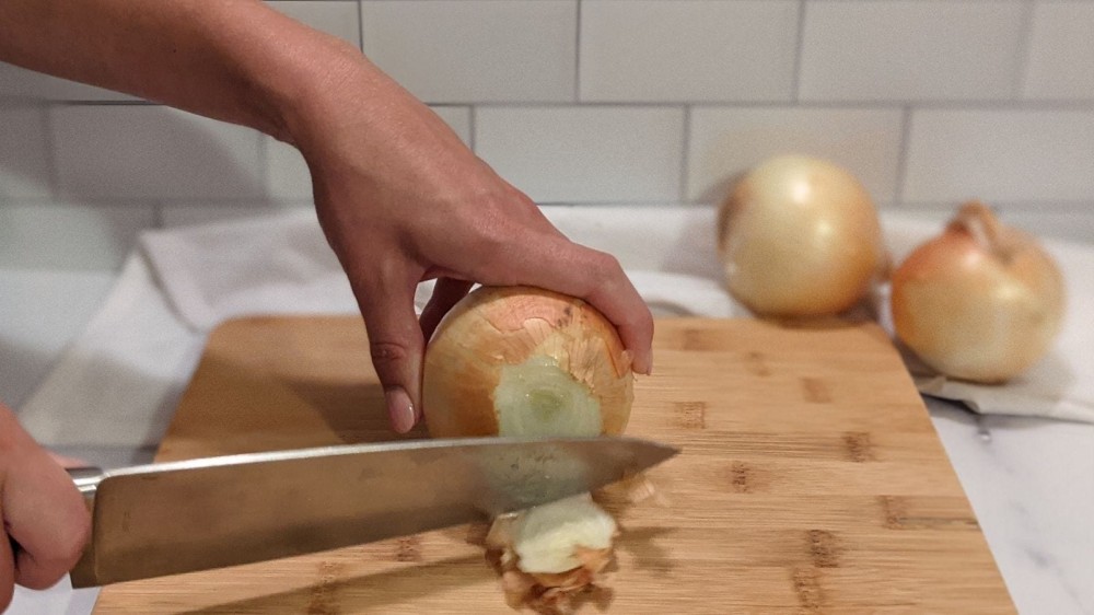 Slicing the stem of an onion off.