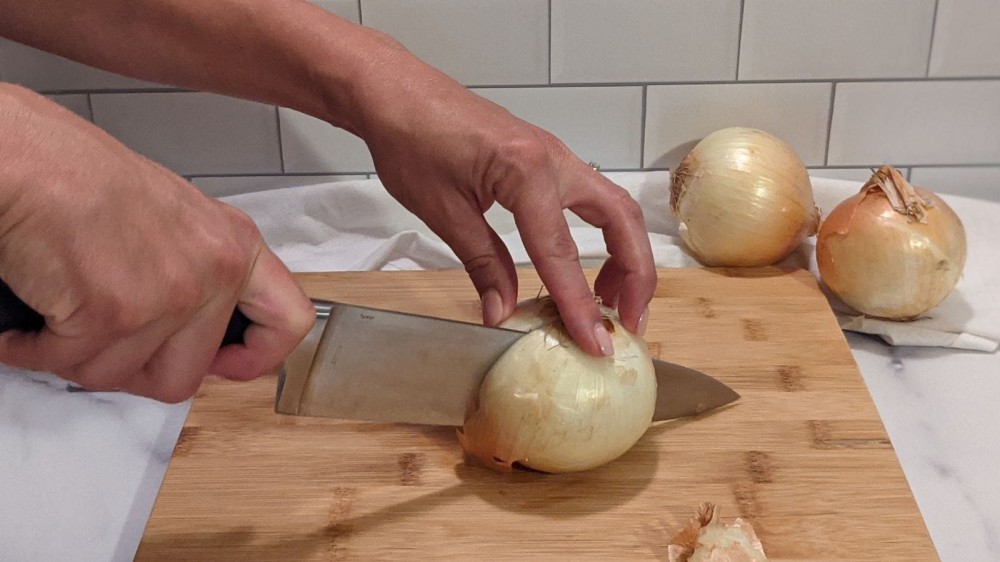 Slicing an onion in half before peeling it. 