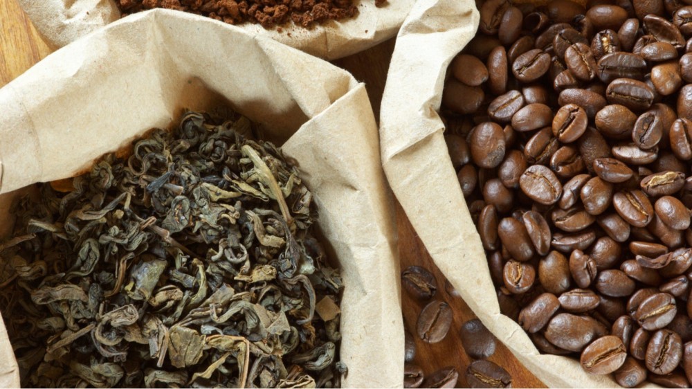 Two paper bags; one filled with tea leaves and the other filled with coffee beans.