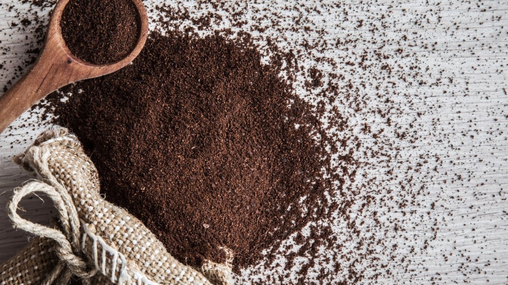 Ground coffee with burlap bag on the wooden table in the kitchen