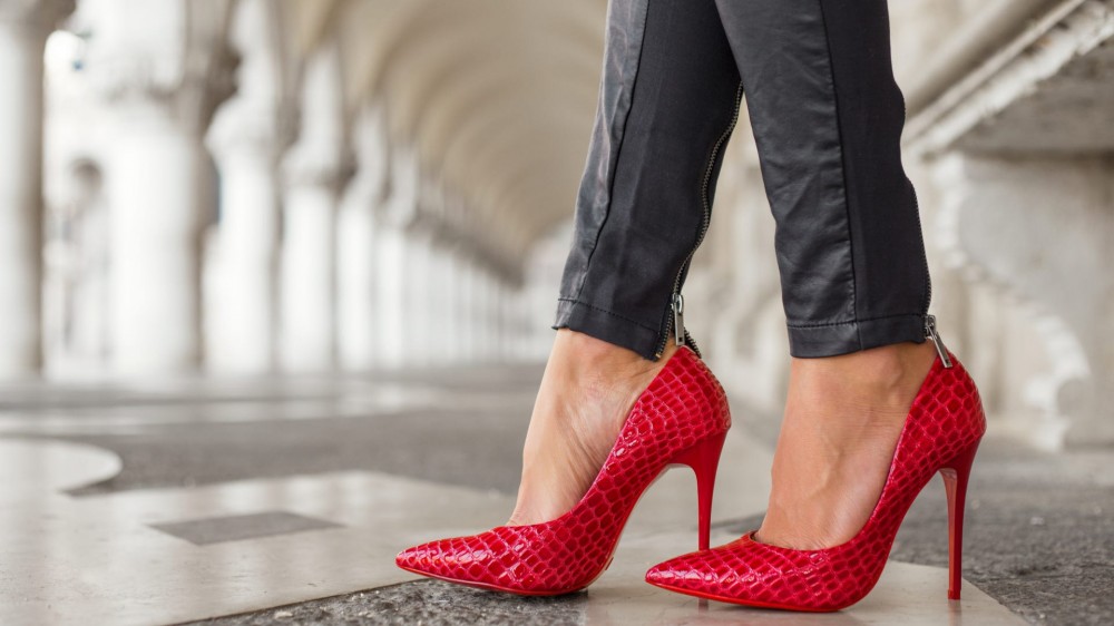 Woman in black leather pants and red high heel shoes