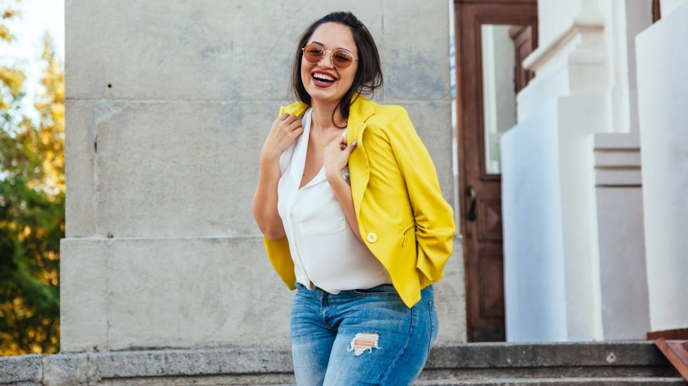 Pretty young woman wearing bright colorful jacket walking on the city street.