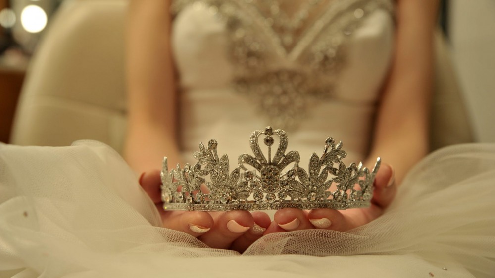 A bride with a tiara in hand.