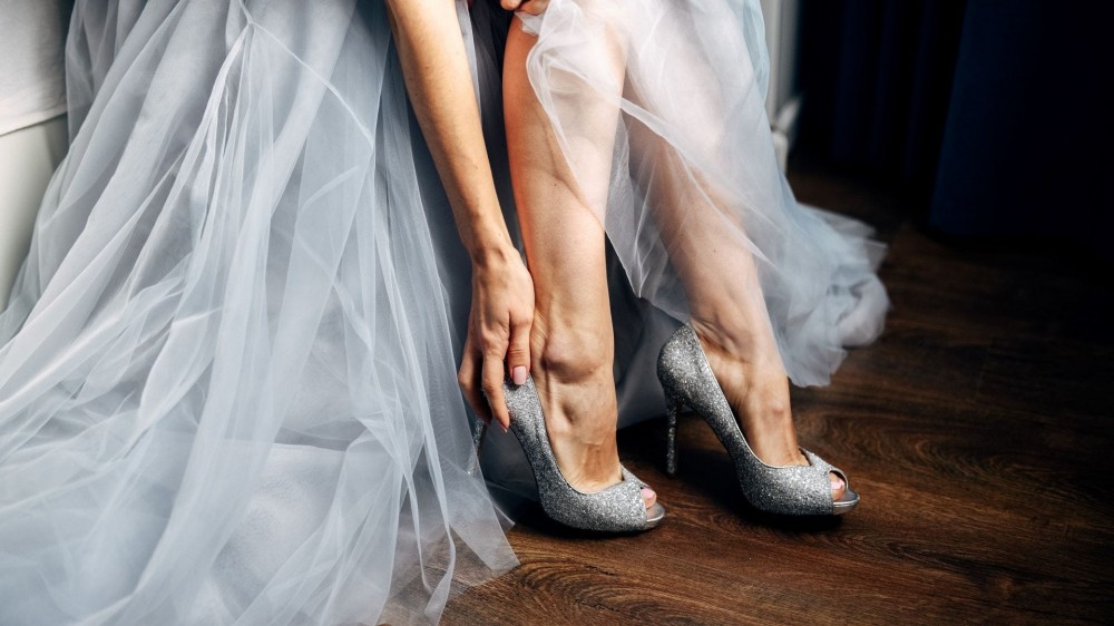 A bride putting on wedding shoes. 