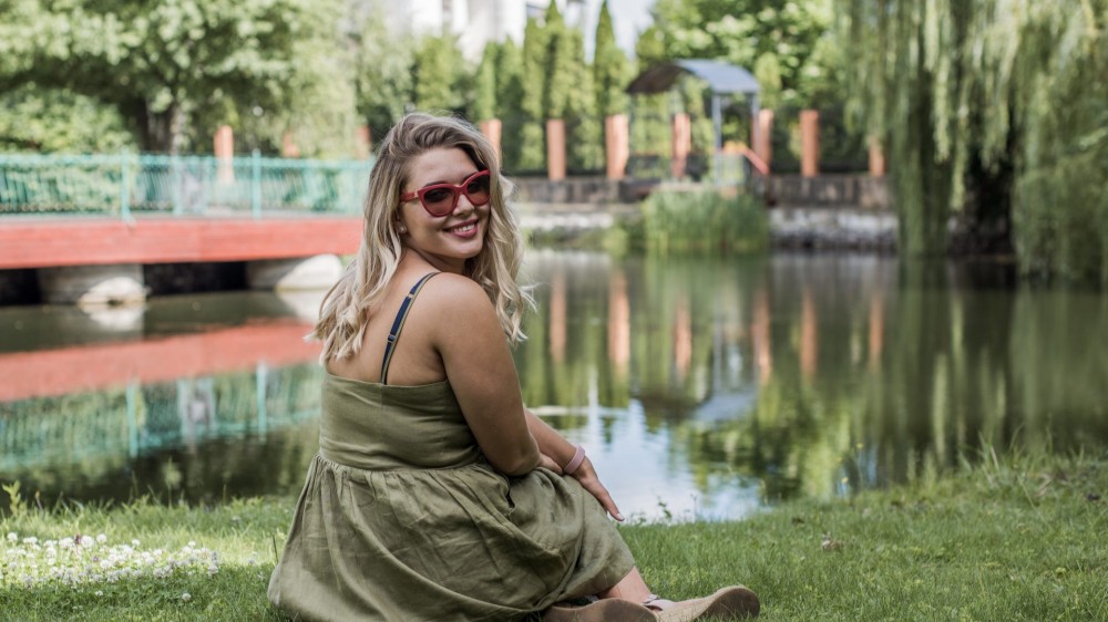 Happy plus size model sitting on grass. 