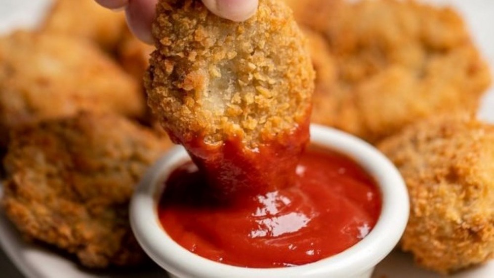 Someone dipping a vegan nugget in ketchup.