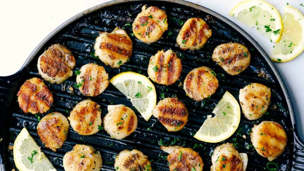 Scallops and lemons on a grill.