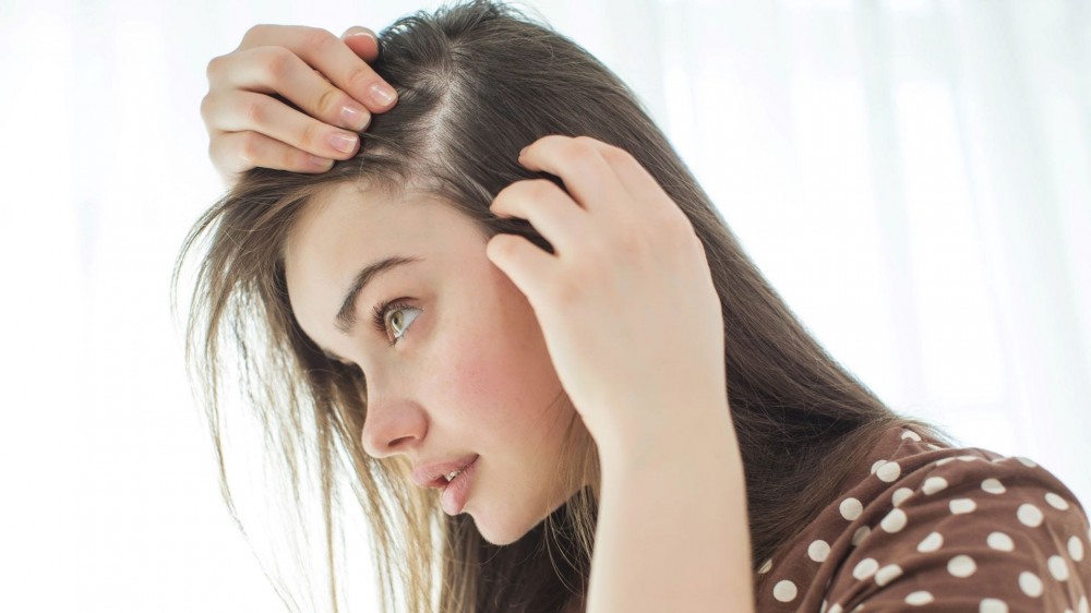 A woman looking at her scalp.