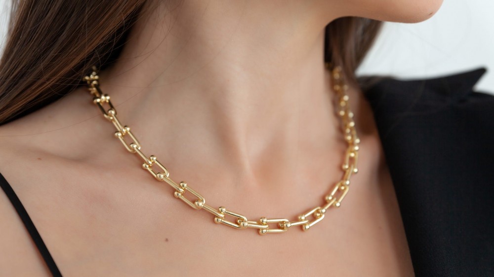 Beautiful model brunette in modern gold metal necklace chain.