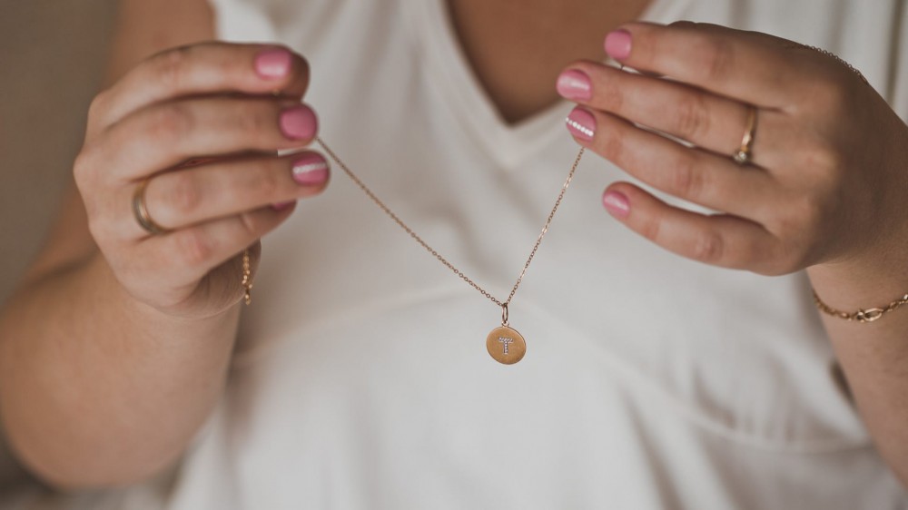 A pair of hands holding up a gold necklace.