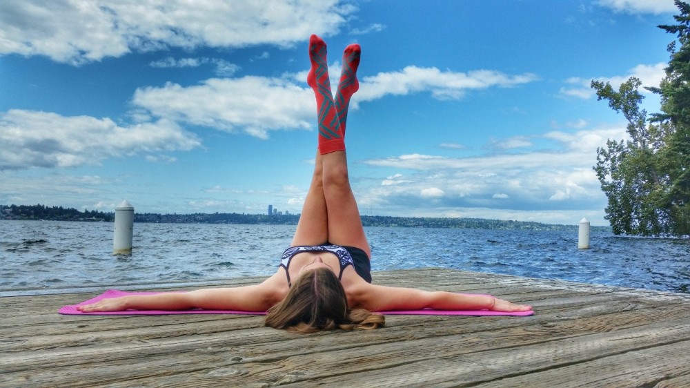 Woman doing legs up the wall pose in front of a lake.