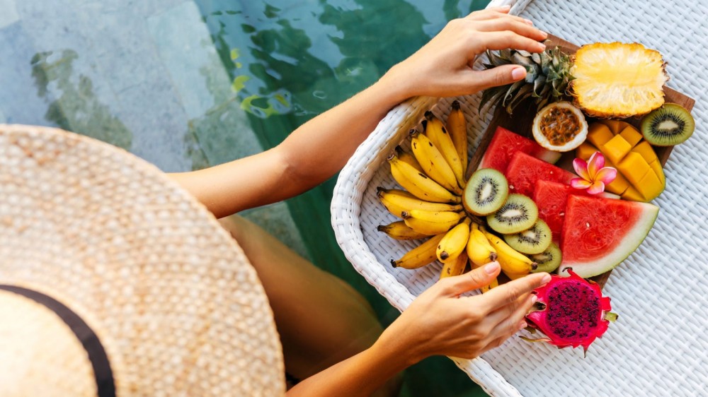 Woman holding a plate of exotic and colorful fruit.