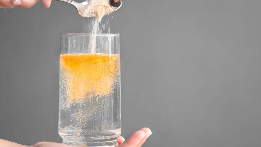 Woman dissolving fiber supplement in water.