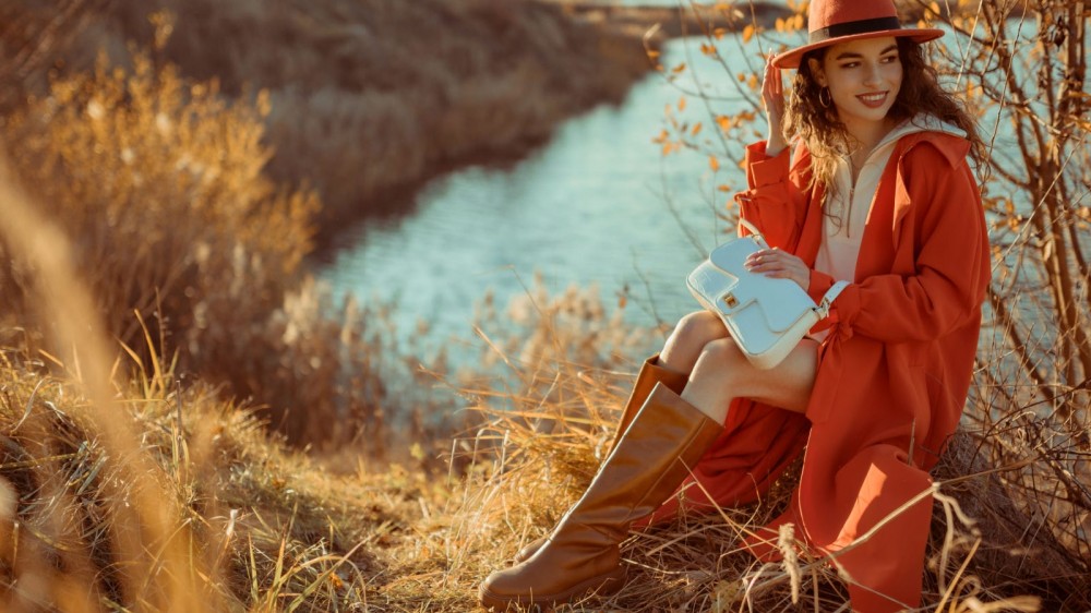 A model wears knee-high brown boots while wearing a red dress.