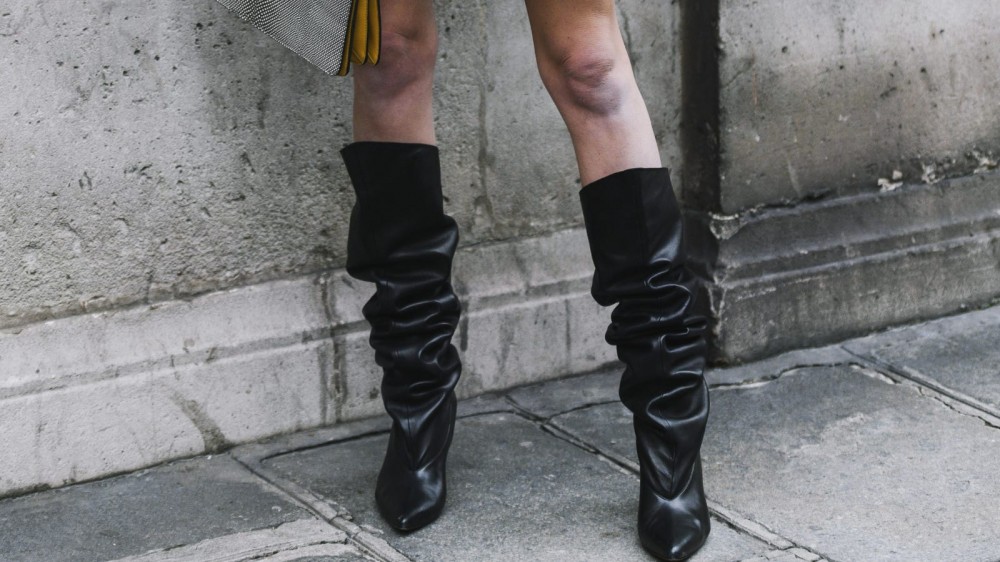 A model wearing a pair of slouchy black boots.