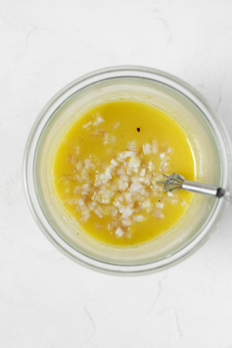 An overhead image of a mason jar, which holds a pale yellow, creamy looking vinaigrette.