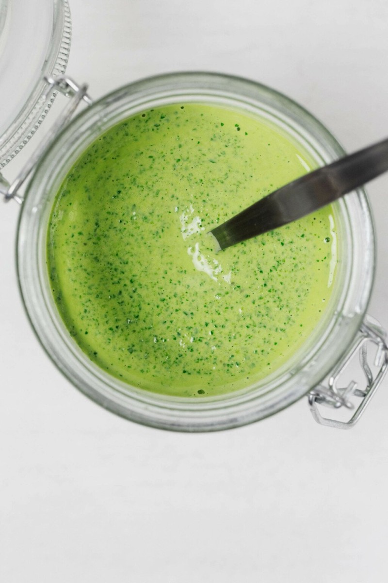 An overhead image of a very bright green sauce, stored in a jar.